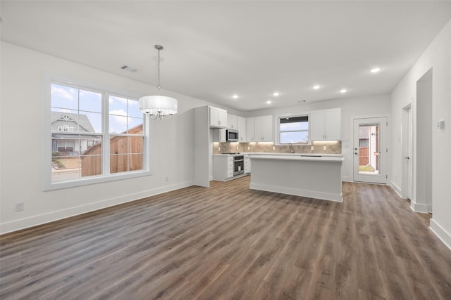 kitchen with a center island, dark hardwood / wood-style floors, appliances with stainless steel finishes, decorative light fixtures, and white cabinetry