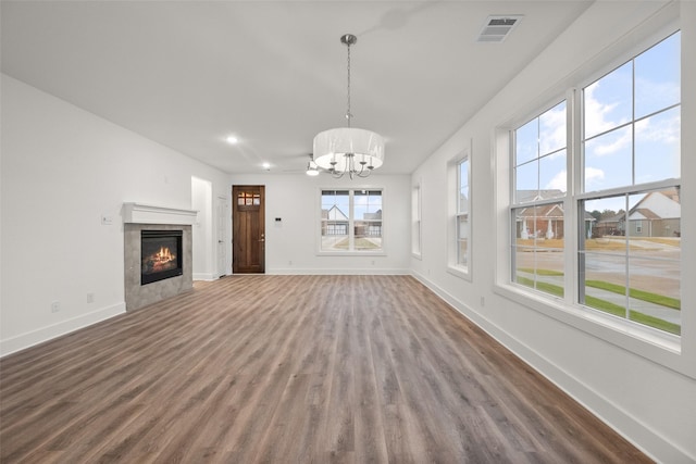 unfurnished living room with a tile fireplace, hardwood / wood-style flooring, and an inviting chandelier