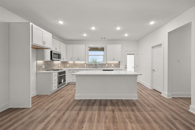 kitchen with white cabinets, wood-type flooring, a center island, and stainless steel appliances