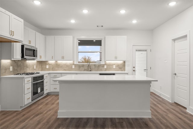 kitchen with a kitchen island, white cabinets, dark hardwood / wood-style floors, and appliances with stainless steel finishes