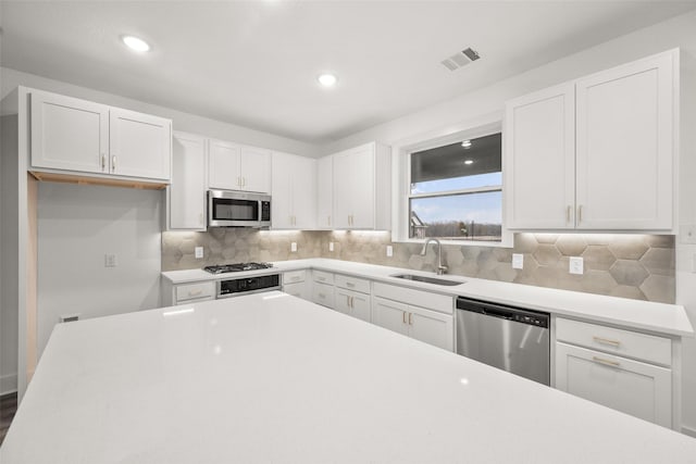 kitchen featuring tasteful backsplash, sink, white cabinets, and stainless steel appliances