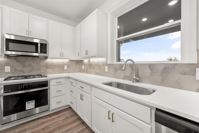 kitchen featuring sink, white cabinets, stainless steel appliances, and hardwood / wood-style flooring