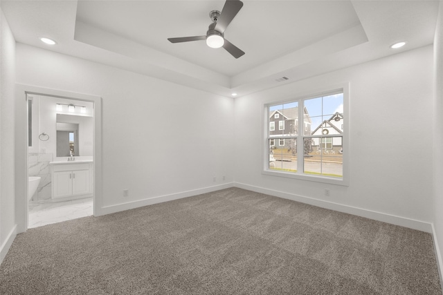 spare room featuring a raised ceiling, ceiling fan, carpet flooring, and sink