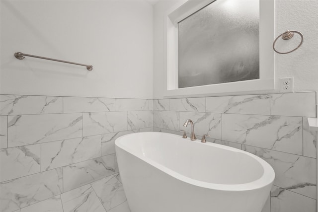 bathroom with a tub and tile walls