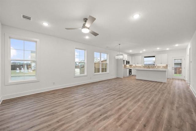 unfurnished living room featuring hardwood / wood-style flooring, ceiling fan, and sink