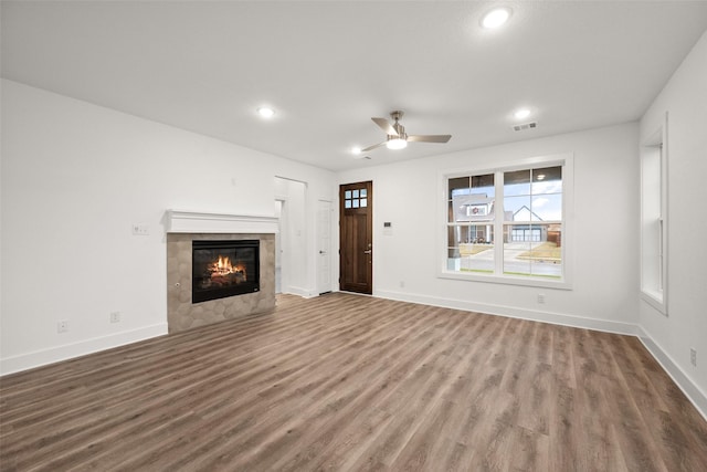 unfurnished living room featuring hardwood / wood-style floors, ceiling fan, and a tiled fireplace