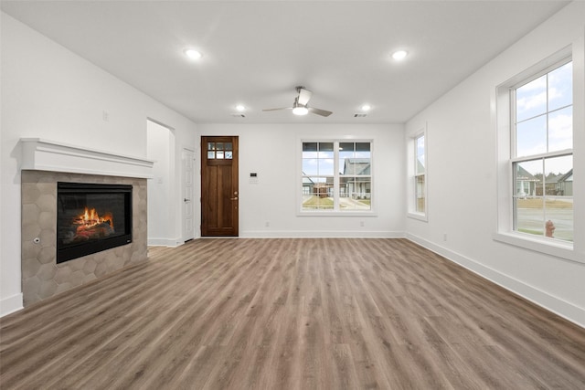 unfurnished living room featuring a tile fireplace, ceiling fan, and hardwood / wood-style floors