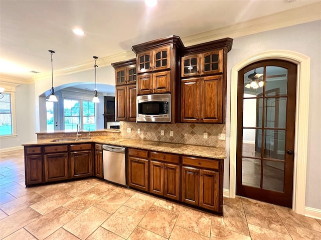 kitchen with sink, tasteful backsplash, crown molding, decorative light fixtures, and appliances with stainless steel finishes