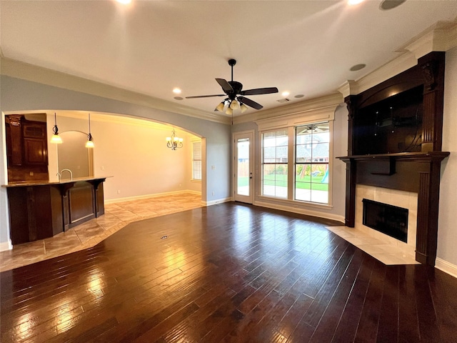 unfurnished living room with a fireplace, ornamental molding, ceiling fan, and light wood-type flooring