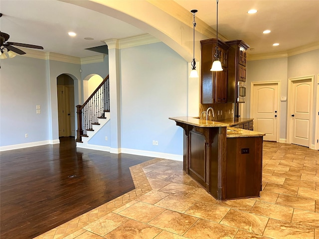 kitchen featuring stainless steel microwave, decorative light fixtures, kitchen peninsula, crown molding, and light stone countertops