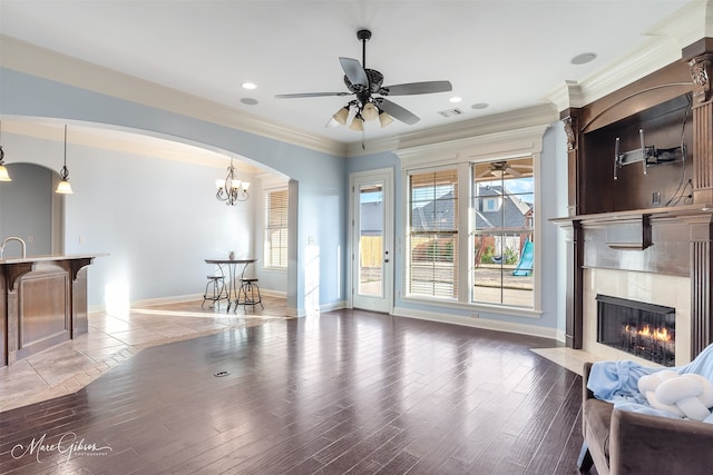 living room with a wealth of natural light, a high end fireplace, ornamental molding, and hardwood / wood-style flooring