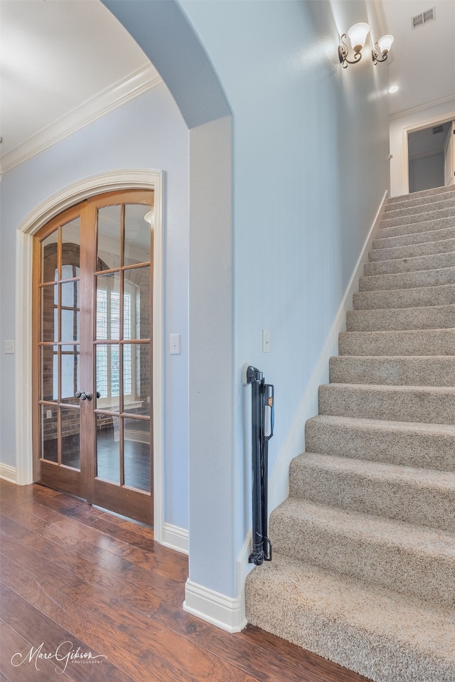 stairway with french doors, ornamental molding, and hardwood / wood-style flooring