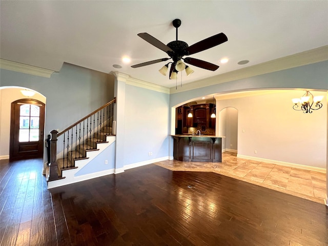 unfurnished living room featuring ornamental molding, ceiling fan with notable chandelier, and wood-type flooring