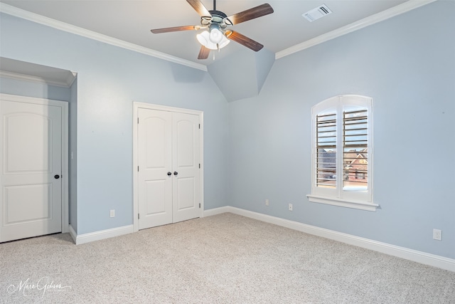 unfurnished bedroom featuring lofted ceiling, ornamental molding, light colored carpet, ceiling fan, and a closet