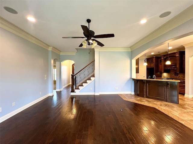 unfurnished living room featuring ornamental molding, dark hardwood / wood-style floors, sink, and ceiling fan