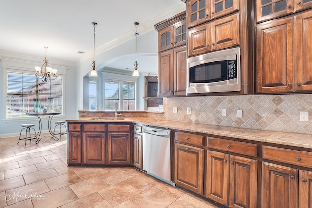 kitchen featuring appliances with stainless steel finishes, decorative light fixtures, sink, backsplash, and light stone countertops