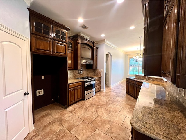 kitchen featuring gas stove, light stone counters, dark brown cabinets, ornamental molding, and decorative backsplash