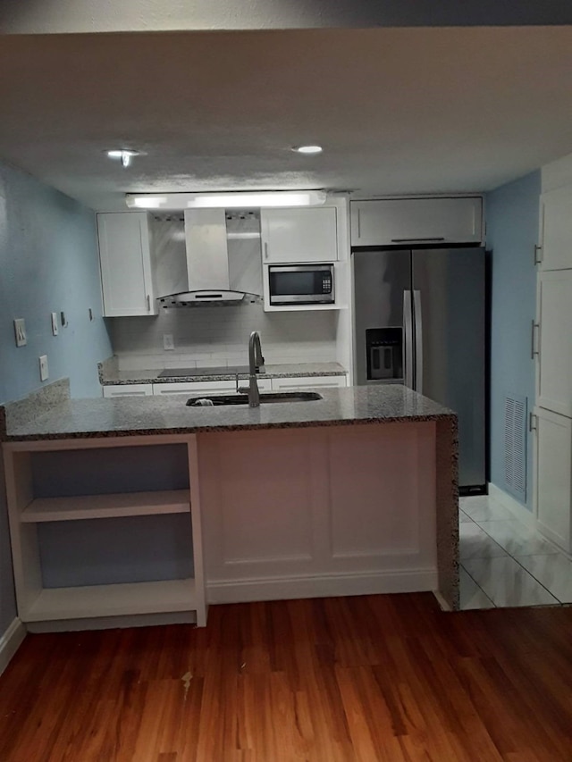 kitchen featuring light hardwood / wood-style floors, stone countertops, and wall chimney range hood