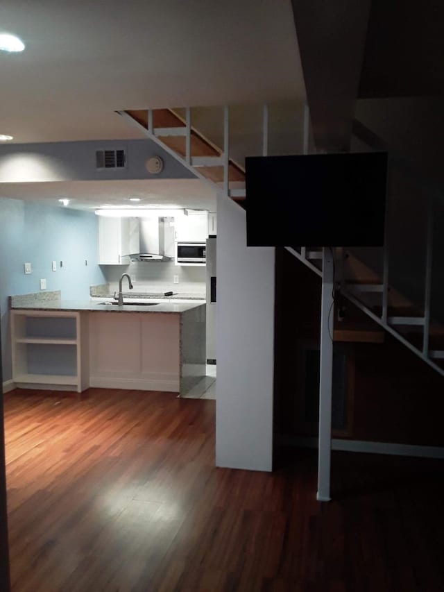 basement with dark wood-type flooring, sink, and refrigerator with ice dispenser