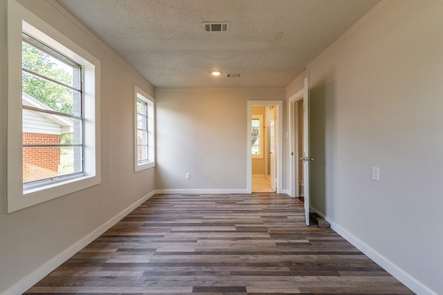 unfurnished room with dark wood-type flooring, a textured ceiling, and a healthy amount of sunlight