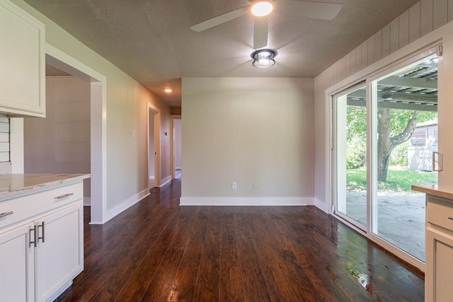 unfurnished dining area featuring ceiling fan, a textured ceiling, and dark hardwood / wood-style flooring