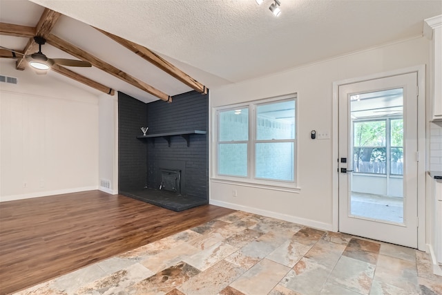 unfurnished living room featuring a fireplace, lofted ceiling with beams, a textured ceiling, and light hardwood / wood-style flooring