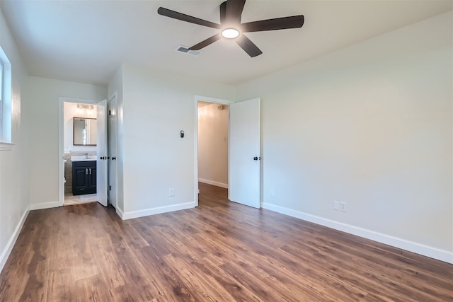 unfurnished bedroom featuring dark hardwood / wood-style flooring, ensuite bath, and ceiling fan