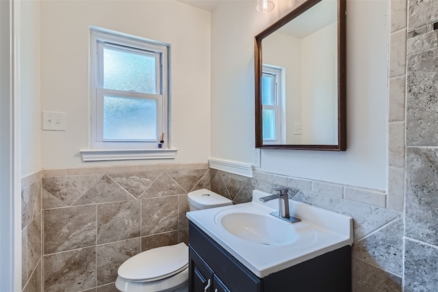 bathroom with vanity, toilet, and tile walls