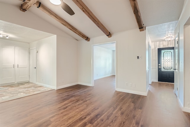 spare room with hardwood / wood-style flooring, a textured ceiling, and vaulted ceiling with beams