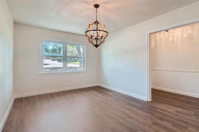 spare room with dark hardwood / wood-style floors, a chandelier, and a textured ceiling