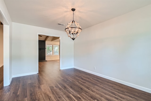 empty room with dark wood-type flooring and a notable chandelier