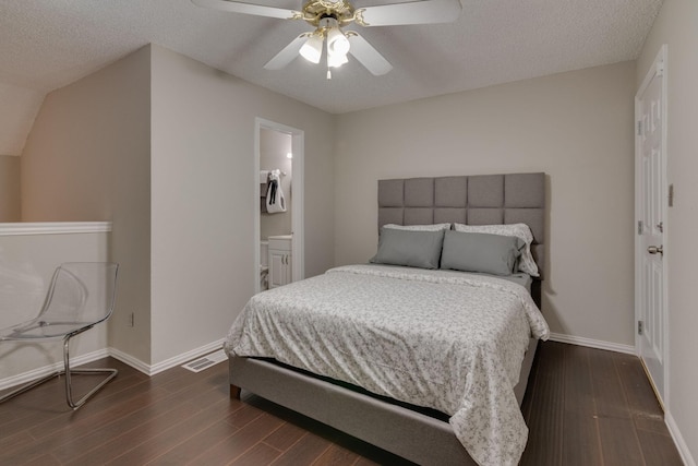 bedroom featuring ceiling fan, ensuite bathroom, dark hardwood / wood-style floors, and a textured ceiling