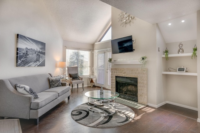 living room featuring built in shelves, vaulted ceiling, a textured ceiling, dark hardwood / wood-style floors, and a tile fireplace