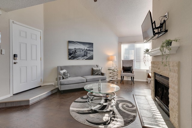 living room featuring vaulted ceiling, a tile fireplace, dark hardwood / wood-style floors, and a textured ceiling