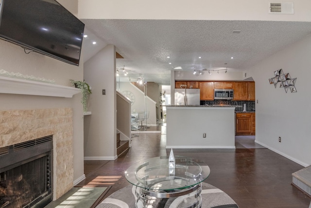 living room featuring high vaulted ceiling, track lighting, and a textured ceiling