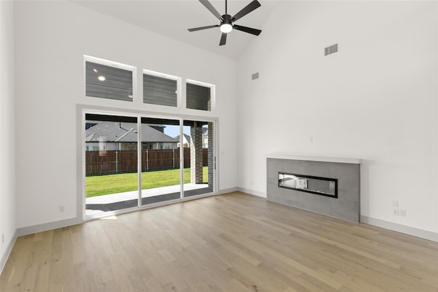 unfurnished living room featuring high vaulted ceiling, light hardwood / wood-style flooring, ceiling fan, and a fireplace