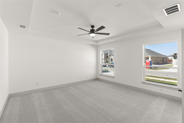 carpeted spare room featuring ceiling fan and a tray ceiling