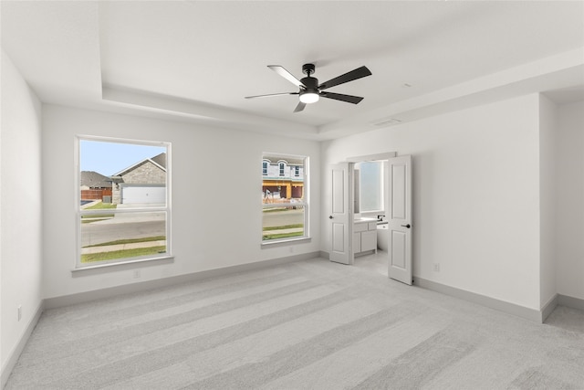 carpeted spare room featuring ceiling fan and a tray ceiling