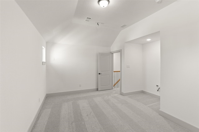 additional living space featuring light carpet and vaulted ceiling