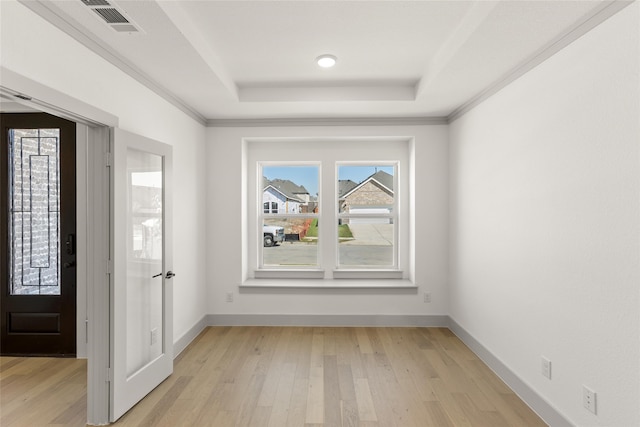 entrance foyer with crown molding, light hardwood / wood-style floors, and a raised ceiling