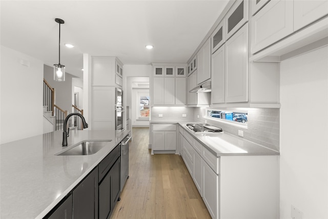 kitchen featuring light hardwood / wood-style floors, white cabinetry, sink, and decorative light fixtures