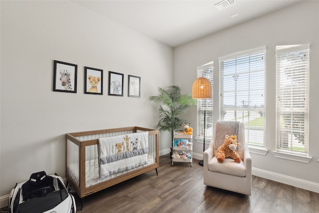 bedroom featuring dark hardwood / wood-style flooring and a nursery area