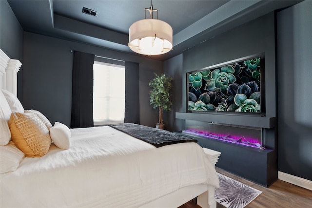 bedroom with hardwood / wood-style flooring and a raised ceiling