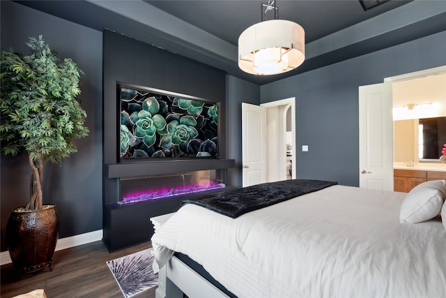 bedroom with ensuite bathroom and dark wood-type flooring