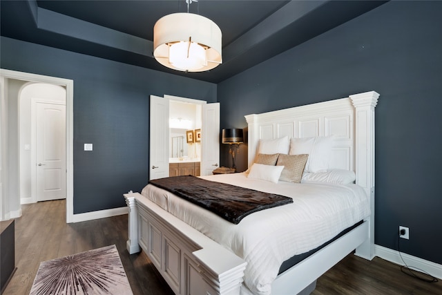 bedroom featuring ensuite bathroom and dark wood-type flooring