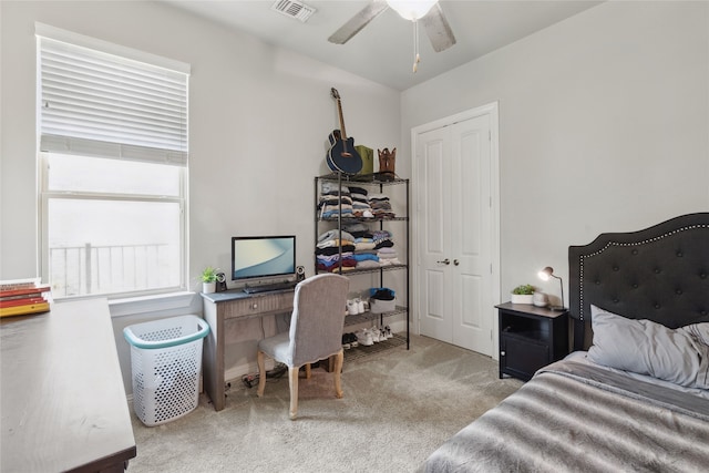 bedroom with ceiling fan, light carpet, and a closet