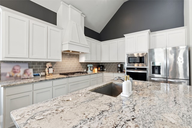 kitchen with white cabinets, light stone counters, and appliances with stainless steel finishes