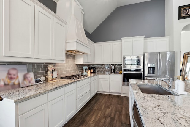 kitchen with premium range hood, high vaulted ceiling, white cabinets, sink, and stainless steel appliances