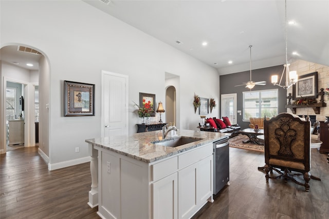 kitchen featuring a kitchen island with sink, sink, stainless steel dishwasher, light stone countertops, and white cabinetry