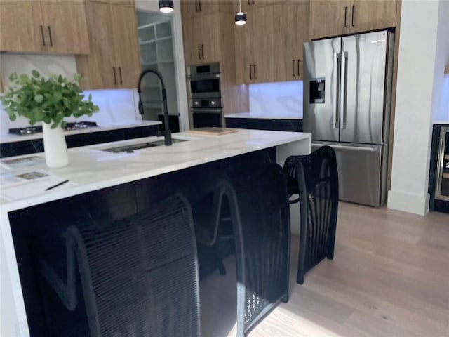 kitchen featuring a breakfast bar, light hardwood / wood-style flooring, stainless steel appliances, and sink